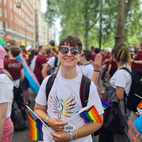 Jack smiling holding Pride flags at a Pride parade