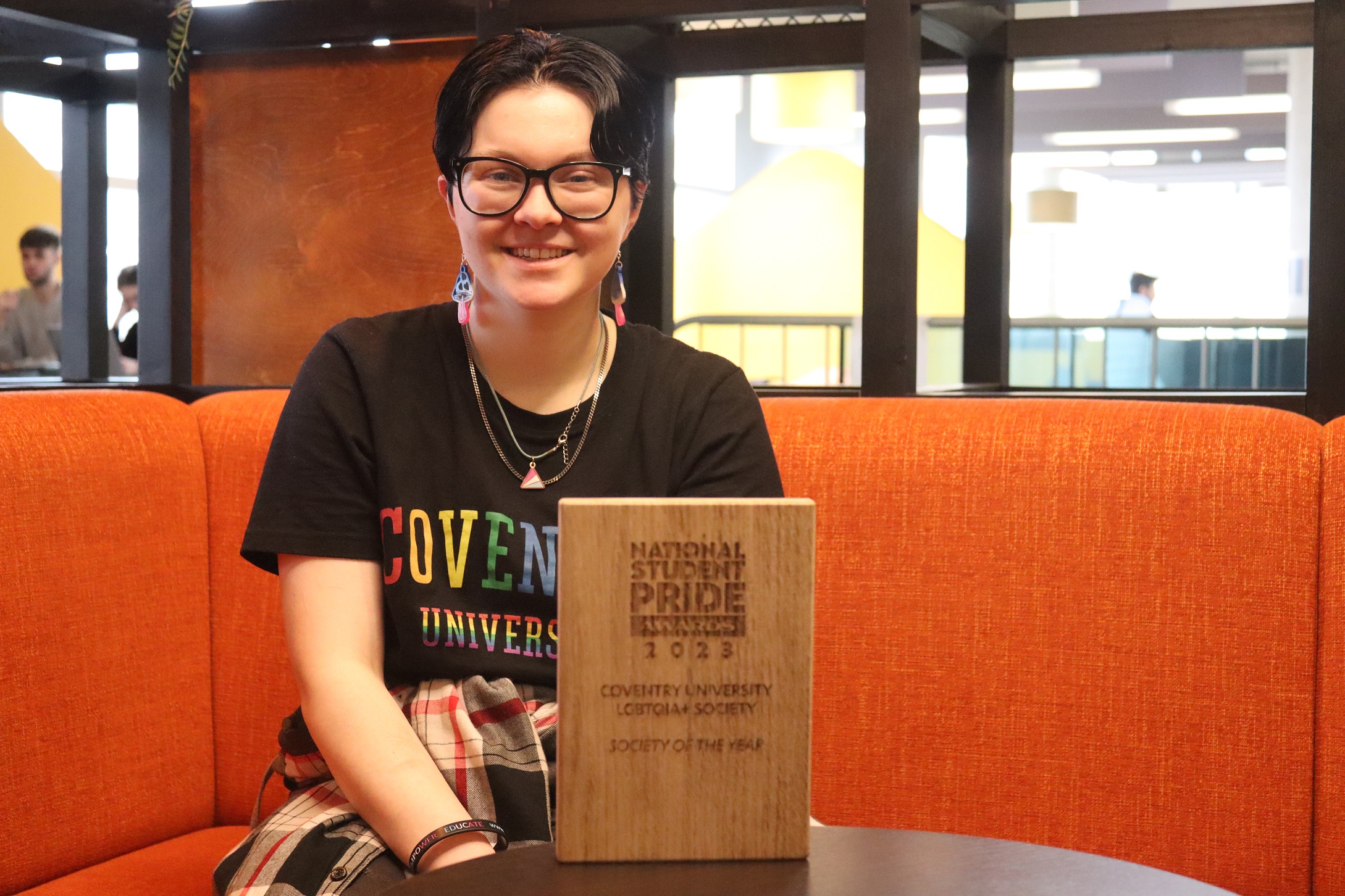 Student sitting on the couch with National Student Pride Award in front of the student lying on the table.