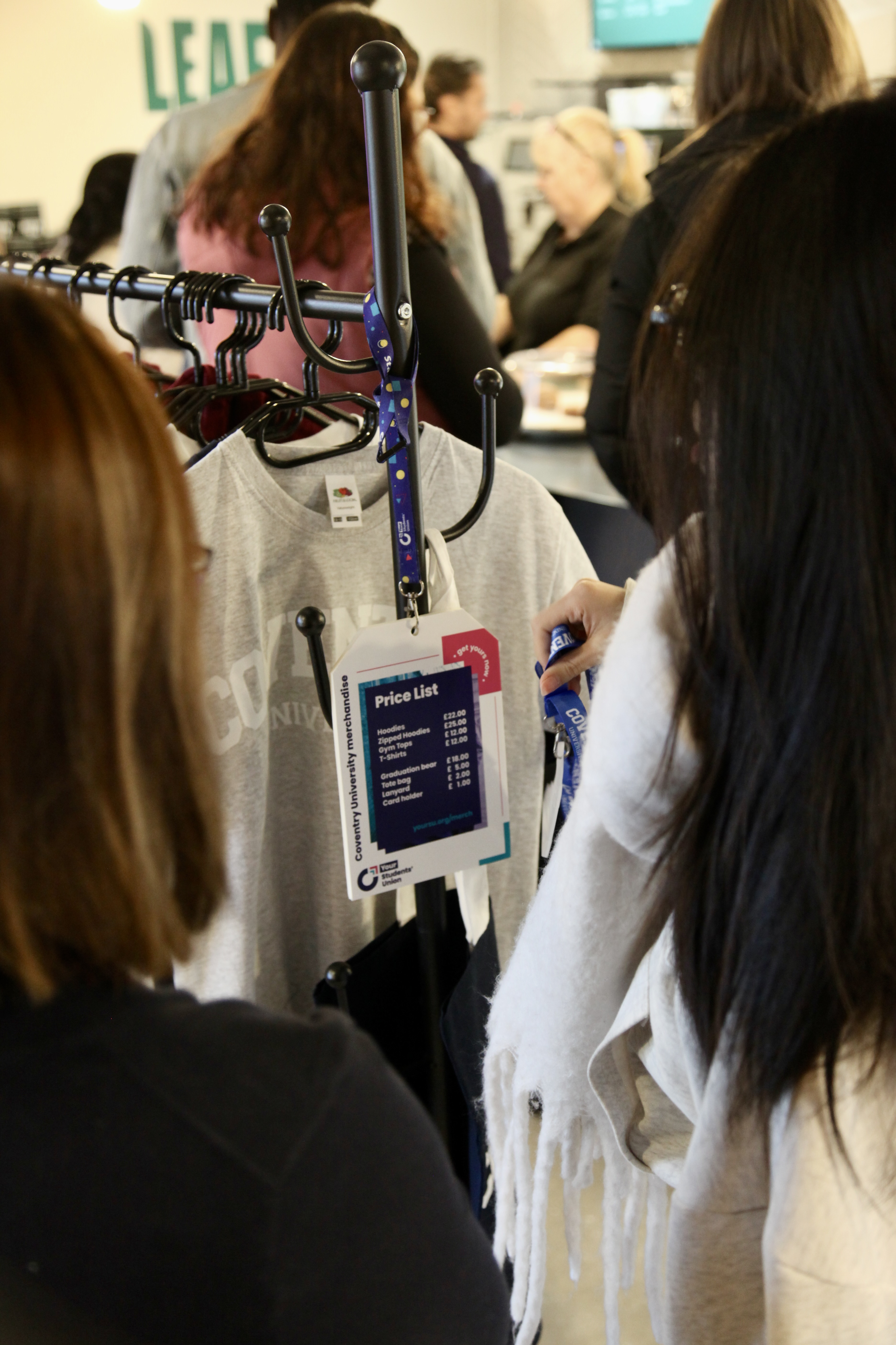Two people looking at a rail with a merchandise price list.