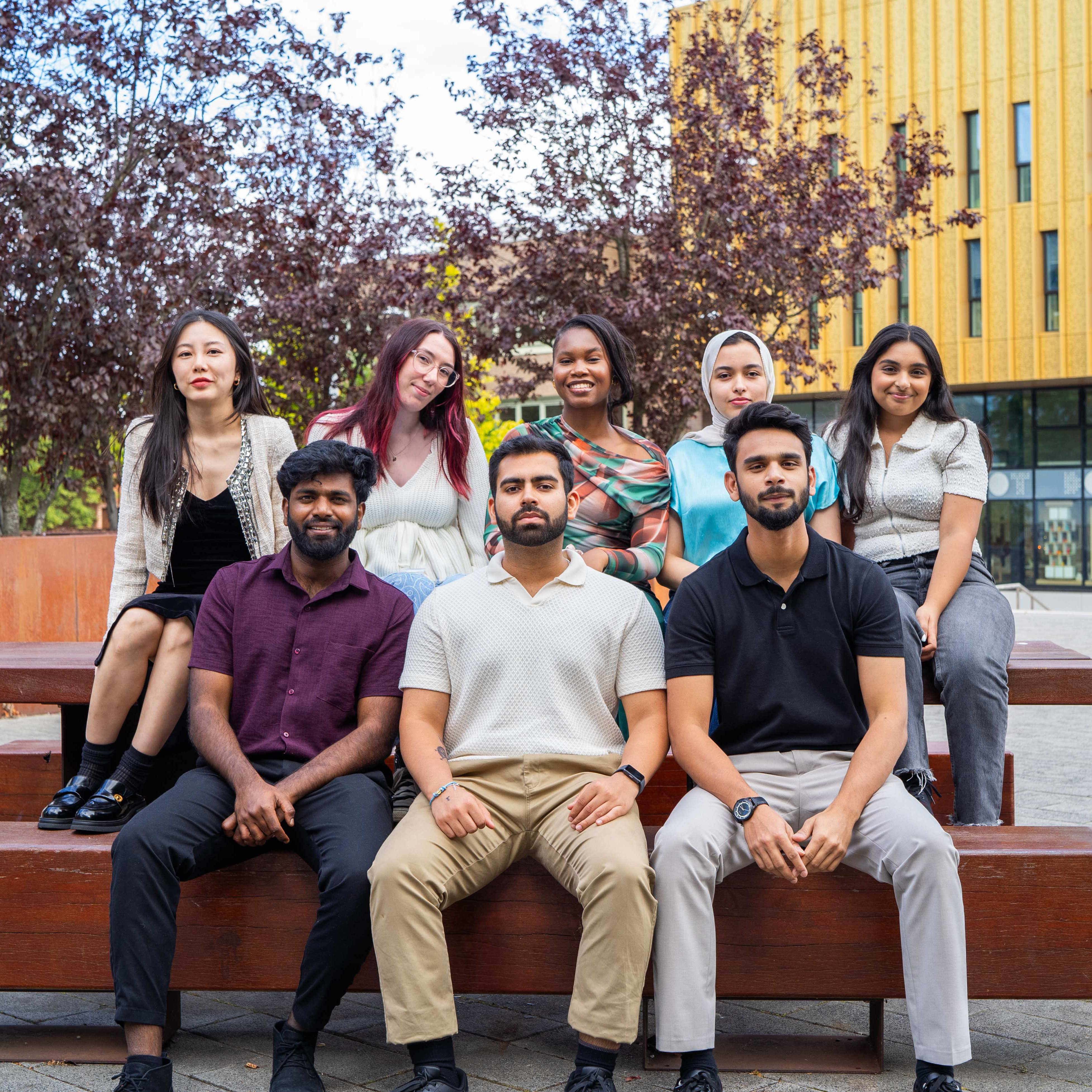 Eight people sat on a bench.
