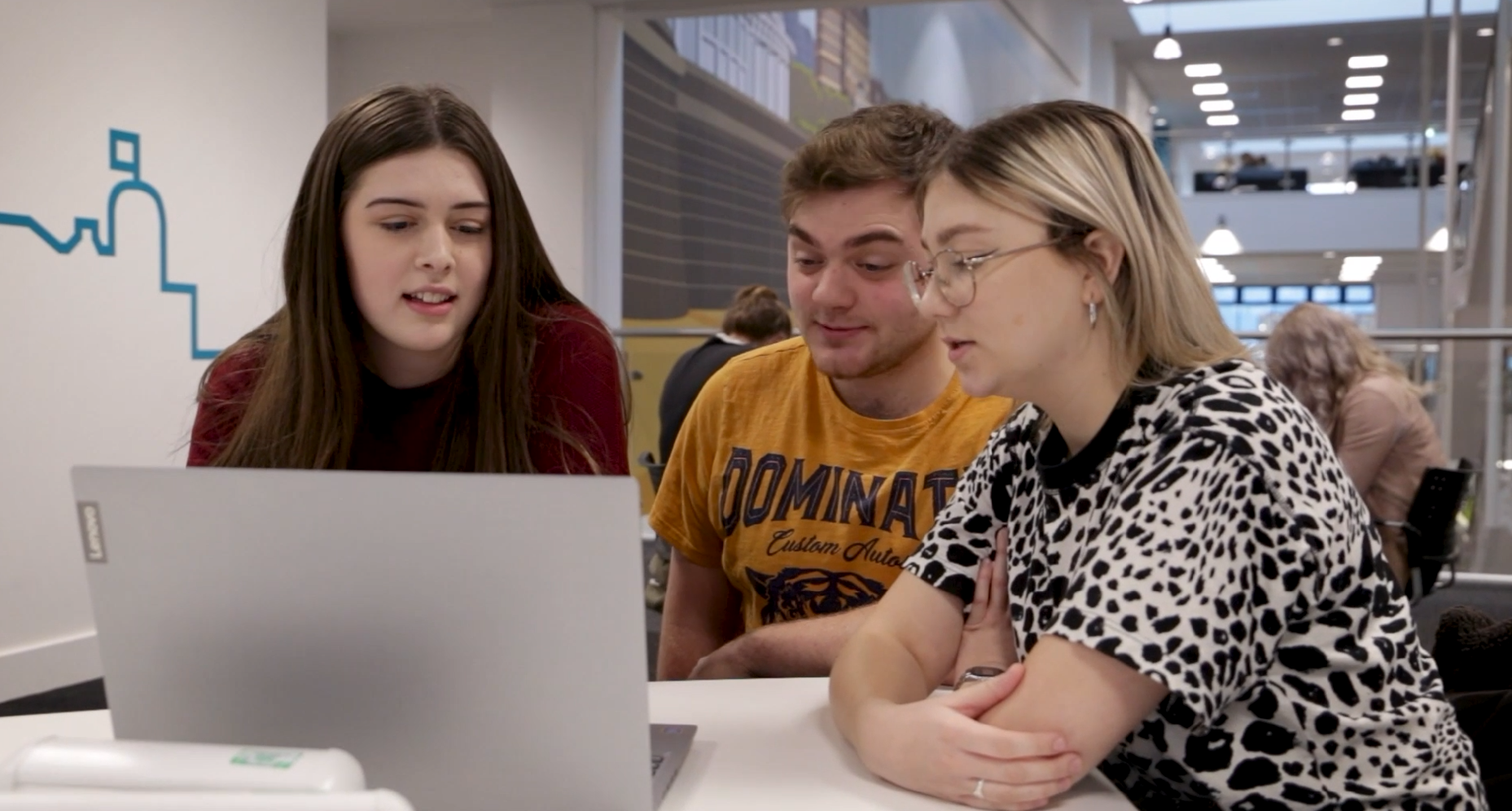 Three people looking at a laptop screen.