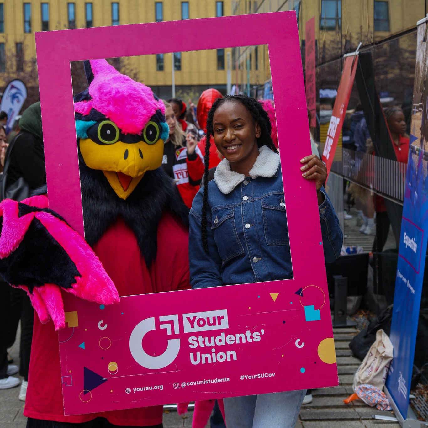 Coventry University Mascot Felix the Phoenix and a person holding a giant 'Your Students' Union' branded photograph template.